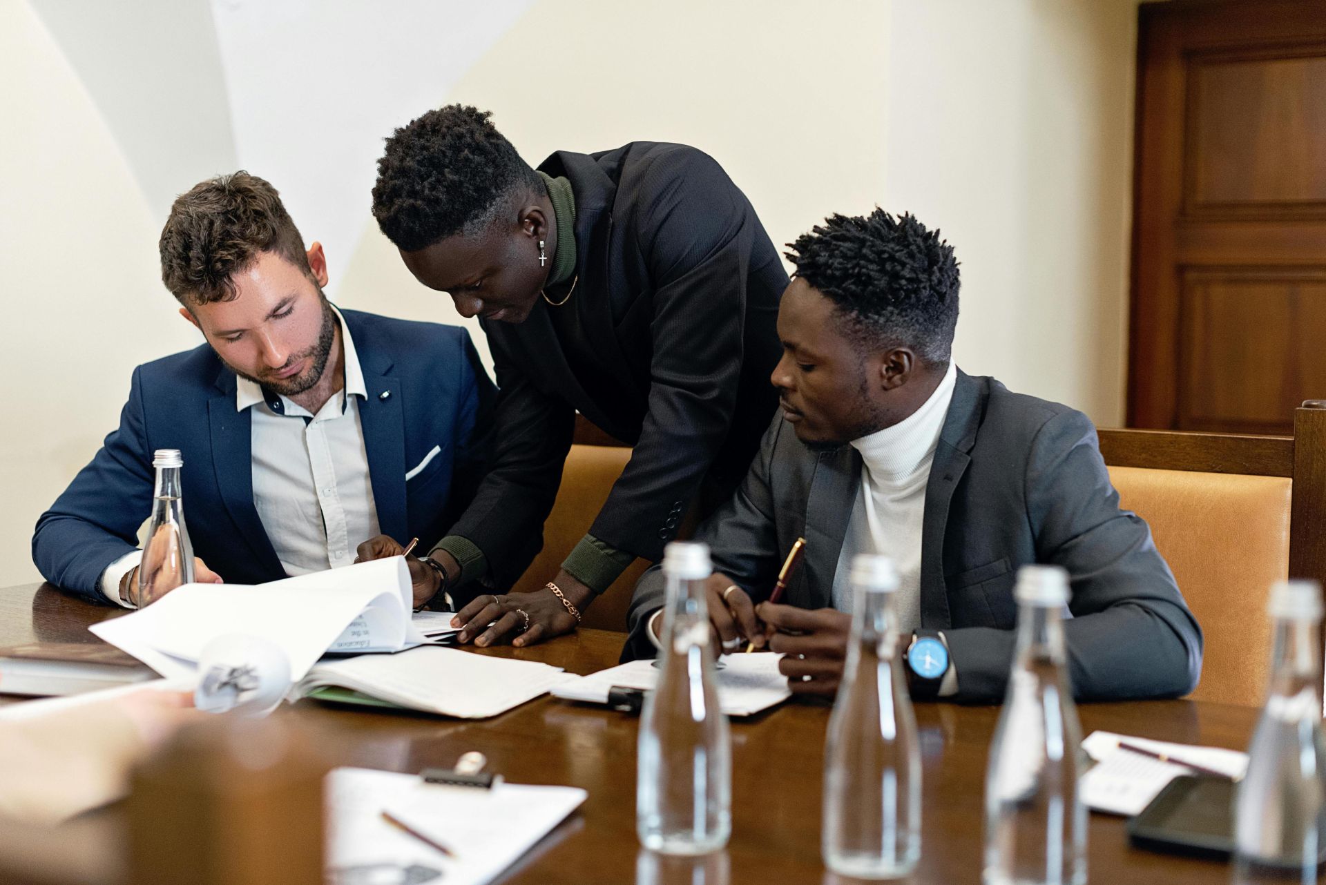Three professionals working together at a table, discussing documents in an office setting.
