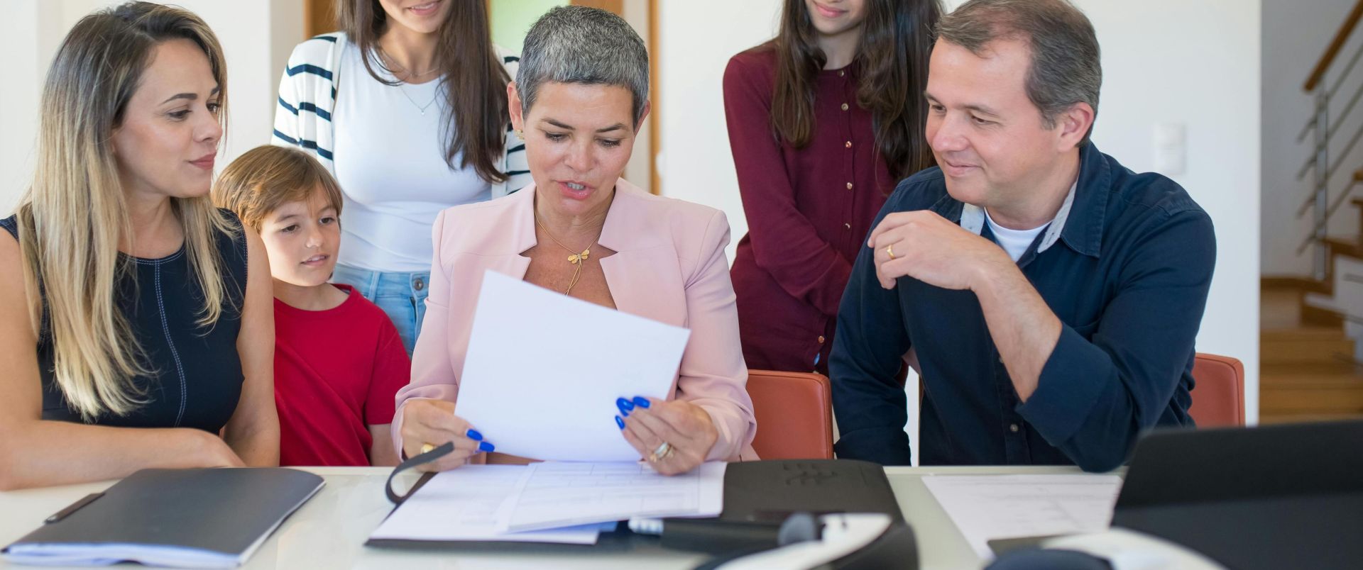 A family meeting with a female realtor reviewing documents in a bright, modern room.